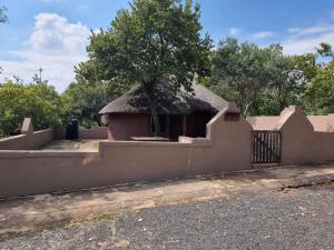 een huis met een rieten dak en een hek bij Out of Africa Lodge in Hartbeespoort