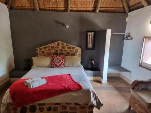 een slaapkamer met een groot bed met een rode deken bij Out of Africa Lodge in Hartbeespoort