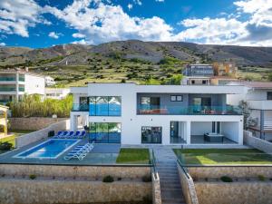 una casa con piscina e montagne sullo sfondo di Villa Prestige a Pag