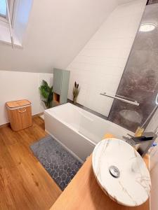 een badkamer met een wit bad en een wastafel bij Le cocon auvergnat in Lapalisse