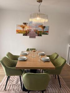 een eettafel met groene stoelen en een kroonluchter bij Le cocon auvergnat in Lapalisse