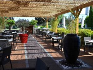 a restaurant with tables and chairs under a pergola at ibis Europe Chalon Sur Saone in Chalon-sur-Saône