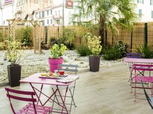 eine Terrasse mit rosa Tischen, Stühlen und Pflanzen in der Unterkunft ibis Bayonne Centre in Bayonne