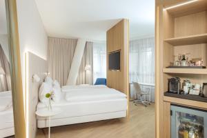 a hotel room with a white bed and a tv at NH Graz City in Graz