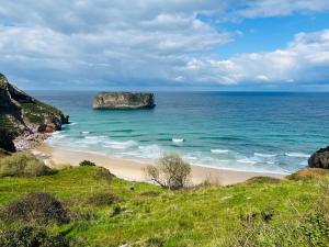 een strand met een grote rots in de oceaan bij Las Mareas de Llanes in Andrín
