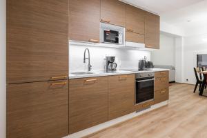 a kitchen with wooden cabinets and a sink and a microwave at Lapland Apartment in Rovaniemi