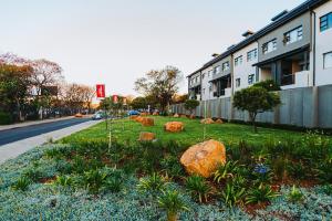 a garden with rocks in the grass in front of a building at Modern Nest in Sandton