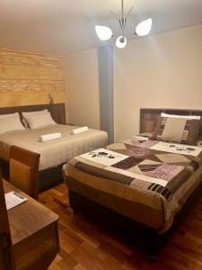 a bedroom with two beds and a table at Hotel Esmeralda in La Paz