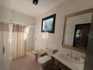 a bathroom with a toilet and a sink and a mirror at Casa Calma Cariló in Carilo +40 photos