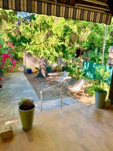 a patio with a table and chairs and a tree at La Bigotière avec clim et jardin in Arles +24 photos
