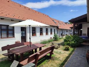 a picnic table with an umbrella in front of a building at Szent Iván Vendégház in Tata