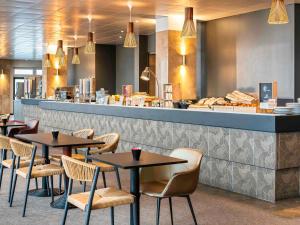 un restaurant avec des tables et des chaises devant un comptoir dans l'établissement ibis Paris porte de Bercy, à Charenton-le-Pont