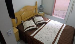 a bedroom with a bed with two pillows and a fan at Triplex no Centro e Pertinho da Praia in Guaratuba
