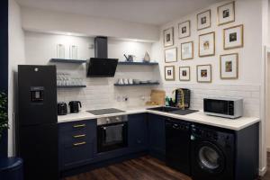 a kitchen with blue cabinets and a black refrigerator at Inbhir Nis City Apartment in Inverness