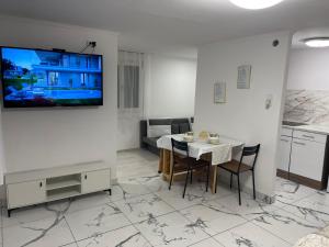 a dining room with a table and a tv on a wall at Rigókert Vendégház in Lakitelek