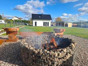 een vuurplaats in een tuin met een huis op de achtergrond bij Dom "Między jeziorami" na Kaszubach, 10 osób, jacuzzi, ognisko, kominek in Grabówko