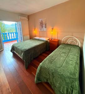 une chambre d'hôtel avec deux lits et un balcon dans l'établissement HOTEL MONTANAS, à Nova Friburgo