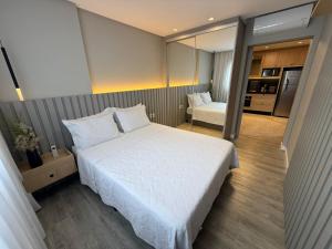 una camera con un grande letto bianco e una cucina di JD Village a Itapema Altre 27 foto