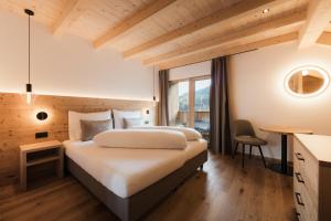 a bedroom with two beds and a table and a chair at Ciasa Bel Marin in La Villa