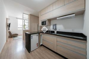 a kitchen with wooden cabinets and a counter top at Studio completo em Barueri - Selenita #8 in Barueri