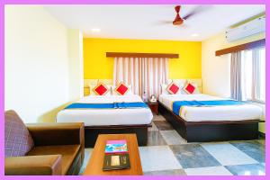ein Hotelzimmer mit zwei Betten und einer Couch in der Unterkunft Hotel Coral Premium Suite Near Jagannath Temple - Sea Beach - Lift Free Parking & Swimming Pool - Best Prime Location Hotel in Puri + 18 Fotos