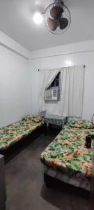 a room with two beds and a ceiling fan at Ma Fremie's Hometel in Lal-lo