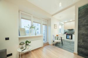 a kitchen and living room with a table and a window at Sandstone Residence - Modern Apartment - 5 min Walk to Beach in Liepāja