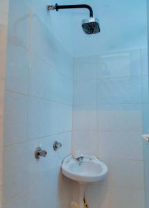 a white bathroom with a sink and a shower at Lumora Deluxe Apartment in Tanga