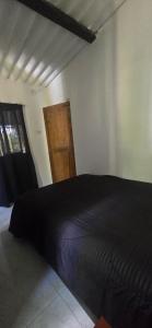 a bedroom with a black bed and a wooden door at Hacienda Popalito in San Rafael