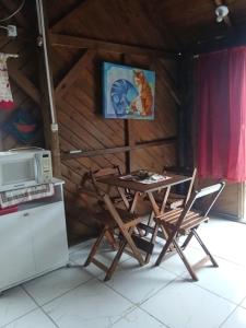 une cuisine avec une table, deux chaises et un four micro-ondes dans l'établissement Cabana 01, à Imbituba 4 autres photos