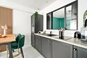 a kitchen with gray cabinets and a sink and a table at Appartement Dinard hyper centre, 2 chambres in Dinard