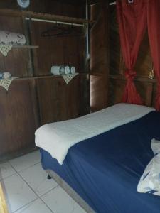 - une chambre avec un lit doté de draps bleus et de rideaux rouges dans l'établissement Cabana 01, à Imbituba