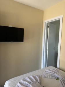 a bedroom with a flat screen tv on the wall at Residencial Lara 9 in Itapema