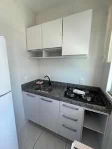 a kitchen with white cabinets and a sink at Residencial Lara 9 in Itapema +4 photos