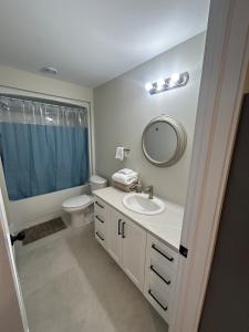 een badkamer met een wastafel, een toilet en een spiegel bij Bright & cozy apartment in Moncton