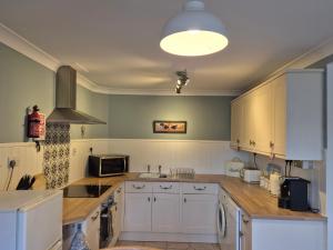 een keuken met witte kasten en een kookplaat oven bij Westgate Cottage in Pickering