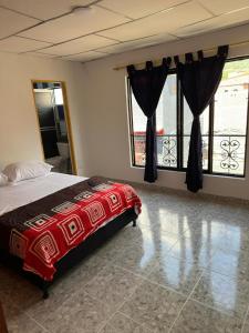 a bedroom with a bed and two windows and a balcony at Hotel y Restaurante More in Supía