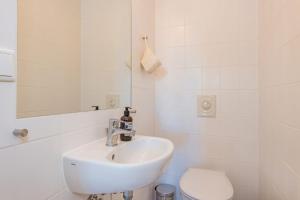 a white bathroom with a sink and a toilet at Haus Dünenwald 17 in Zinnowitz +8 photos