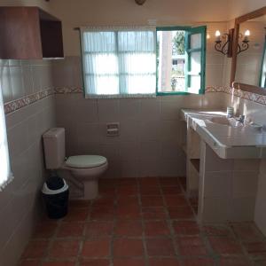 een badkamer met een toilet, 2 wastafels en een raam bij Mya Esencia Espacio Eco Turístico Camping in Tinquipaya +23 foto's