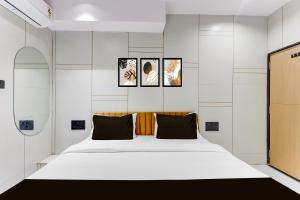 a bedroom with a large white bed with three pictures on the wall at Hotel O jalsha in Surat