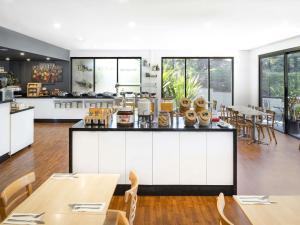 Una cocina y un comedor con mesas y sillas. en ibis Thornleigh, en Thornleigh