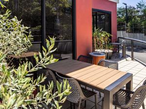 una mesa de madera y sillas en un patio con plantas en ibis Thornleigh, en Thornleigh