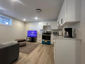 een keuken met witte kasten en een tafel en een tv bij Modern Private Suite in Moncton