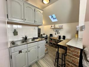 a kitchen with white cabinets and a sink and a counter at Le Comfy Studio Central proche Disney & Paris in Lagny