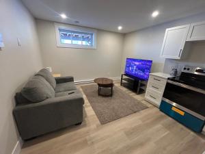 een woonkamer met een bank en een tv bij Bright & cozy apartment in Moncton