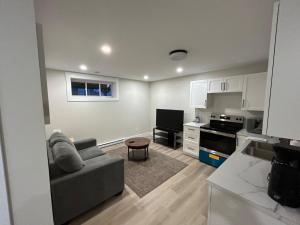 een woonkamer met een bank en een keuken bij Bright & cozy apartment in Moncton