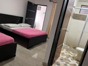 a small bedroom with two beds and a shower at Hotel La Realeza in Barbosa