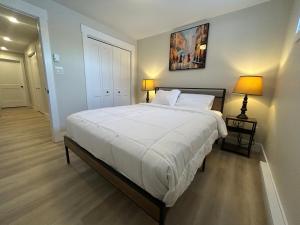 een slaapkamer met een groot wit bed met twee lampen bij Bright & cozy apartment in Moncton