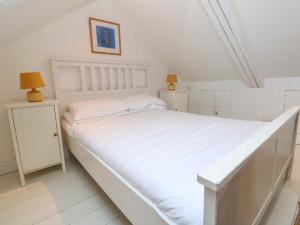 a white bedroom with a large bed and two night stands at Badgers Loft in Penzance
