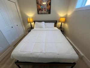 een slaapkamer met een groot wit bed met twee lampen bij Modern Private Suite in Moncton
